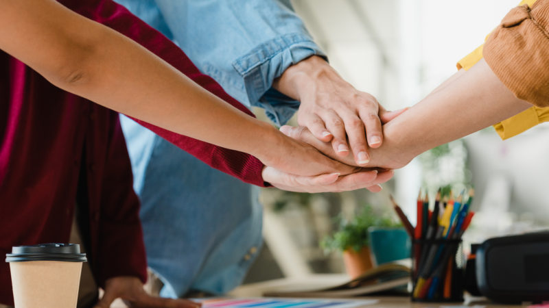 Asian businessmen and businesswomen meeting brainstorming putting hands up for new startup and giving strength motivation working together in modern creative office. Coworker teamwork concept. Asian businessmen and businesswomen meeting brainstorming puttin
