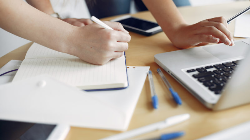 Two girls in a white t-shirts working at the office